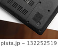 Upside down black laptop with cooling vents and screw mounts on white table 132252519