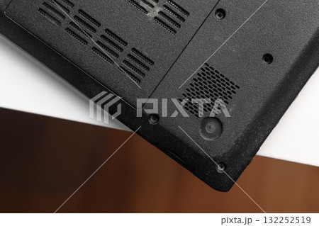 Upside down black laptop with cooling vents and screw mounts on white table Upside down black laptop with cooling vents and screw mounts on white table 132252519