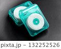 Dental floss in green plastic cases on black ceramic close up 132252526