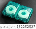 Two rolls of dental floss in green plastic cases on black close up 132252527