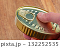 Metal can of preserved tuna fish in man hand over wooden table close up 132252535