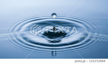 Water drop falling on calm blue water surface creating ripples for concept of purity, clarity, zen, meditation and wellness Water drop falling on calm blue water surface creating ripples for concept of purity, clarity, zen, meditation and wellness 132252668