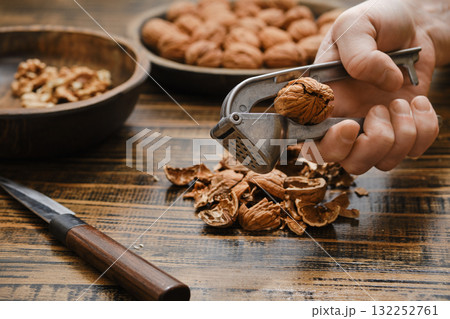 Hand cracking walnuts with nutcracker in a kitchen setting during the afternoon 132252761