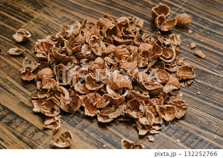 Pile of brown nutshells scattered on wooden surface during snack time at home Pile of brown nutshells scattered on wooden surface during snack time at home 132252766