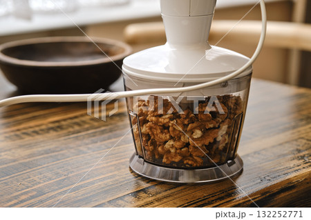 Chopping walnuts in a food processor on a wooden table at home Chopping walnuts in a food processor on a wooden table at home 132252771
