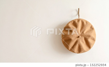 アイボリーの壁にかけられたベージュのベレー帽、シンプルで静かな日常のワンシーン 132252934