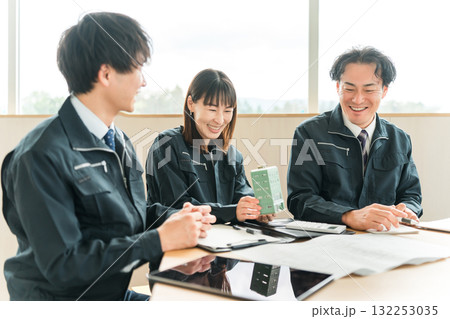 ビルの模型を見ながら会議,ミーティングする作業着姿の男女のビジネスマン ビルの模型を見ながら会議,ミーティングする作業着姿の男女のビジネスマン 132253035