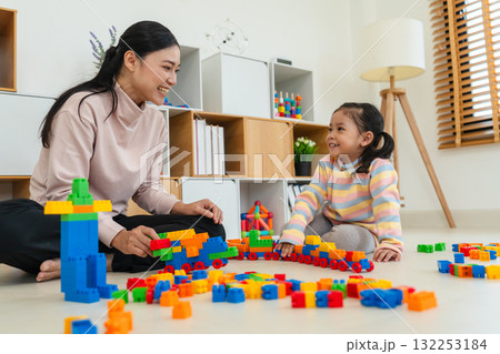 happy toddler girl and mother playing building blocks or plastic bricks toy at home 132253184