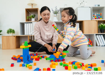 happy toddler girl and mother playing building blocks or plastic bricks toy at home 132253186