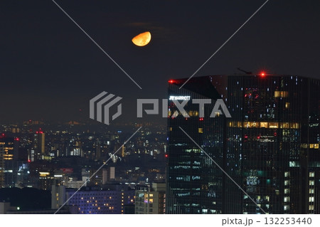 Early half harvest moon in Tokyo over the new Takanawa Gateway Marriott Hotel in the early evening in Minato-ku Tokyo Japan 132253440