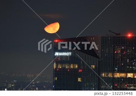 Early half harvest moon in Tokyo over the new Takanawa Gateway Marriott Hotel in the early evening in Minato-ku Tokyo Japan Early half harvest moon in Tokyo over the new Takanawa Gateway Marriott Hotel in the early evening in Minato-ku Tokyo Japan 132253448