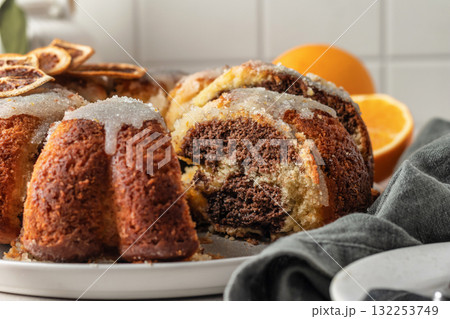 Sliced orange and chocolate bundt cake with sugar icing. Fruity citrus dessert on light gray kitchen background Sliced orange and chocolate bundt cake with sugar icing. Fruity citrus dessert on light gray kitchen background 132253749
