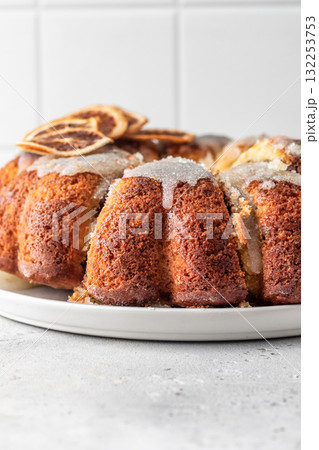 Orange and chocolate marble bundt cake with sugar icing close up. Fruity citrus dessert on light gray kitchen background Orange and chocolate marble bundt cake with sugar icing close up. Fruity citrus dessert on light gray kitchen background 132253753