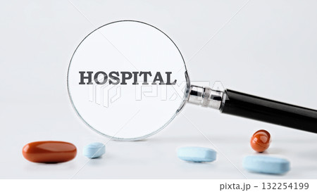 A close-up view featuring a magnifying glass focusing on the word hospital. Colorful pills of various shapes and sizes lie around, suggesting a connection to health and wellness A close-up view featuring a magnifying glass focusing on the word hospital. Colorful pills of various shapes and sizes lie around, suggesting a connection to health and wellness 132254199