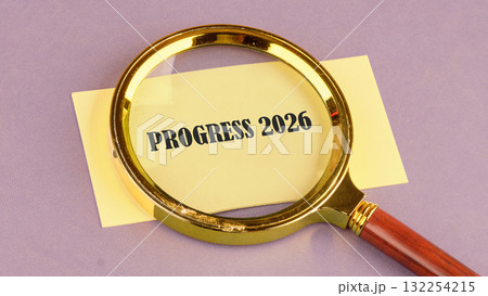 A golden magnifying glass highlights the words Progress 2026 written on a yellow piece of paper. The scene is set against a soft purple backdrop, creating an artistic atmosphere A golden magnifying glass highlights the words Progress 2026 written on a yellow piece of paper. The scene is set against a soft purple backdrop, creating an artistic atmosphere 132254215