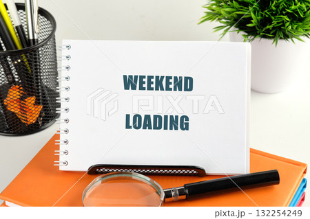 A sign reading weekend loading rests on an organized desk surrounded by stationery and a small green plant, evoking excitement for the approaching break and relaxation A sign reading weekend loading rests on an organized desk surrounded by stationery and a small green plant, evoking excitement for the approaching break and relaxation 132254249