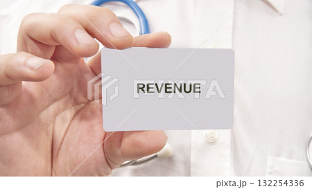A person holds a card with the word revenue prominently displayed, set against a backdrop of healthcare tools, capturing the essence of financial discussions in medical environments A person holds a card with the word revenue prominently displayed, set against a backdrop of healthcare tools, capturing the essence of financial discussions in medical environments 132254336