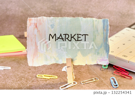 A handmade market sign sits on a desk surrounded by colorful paper clips and sticky notes. This setup reflects the organization of local events and community sales in a creative way 132254341