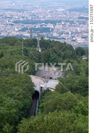 Panoramic view from Moiwa mountain, Train entering tunnel in forested mountain area overlooking cityscape at Sapporo, Hokkaido, Japan 132255897