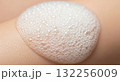 An extreme close-up shows white foam or cleanser bubbles being massaged over the cheek and mouth area of a person's face. 132256009