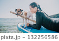 Woman Dog Paddleboard Smiling woman and dog enjoy paddleboarding on the water. 132256586