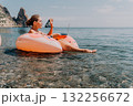 Woman, Float, Sea - Young woman relaxing on a pink float in the sea on a sunny day. 132256672