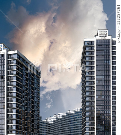 Building stands tall under cloudy sky. Modern concrete multistorey block features patterned window 132257261