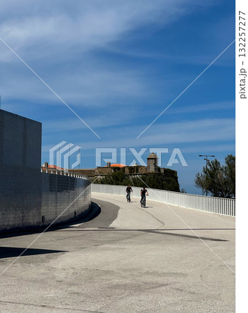 Cycling on bicycles in historic coastal city. Two cyclists ride down concrete road slope near Cycling on bicycles in historic coastal city. Two cyclists ride down concrete road slope near 132257277