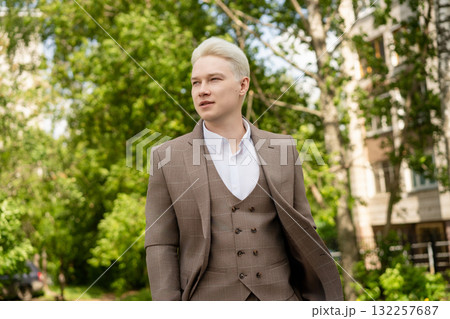 Young man in brown suit walking through vibrant green park on sunny day Young man in brown suit walking through vibrant green park on sunny day 132257687
