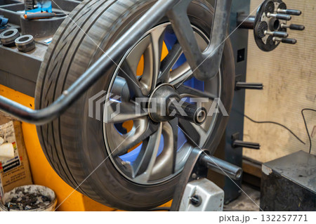 Car wheel rotating on a balancing machine during seasonal tire service at an auto workshop. Essential step to ensure smooth driving and tire longevity before winter installation. 132257771