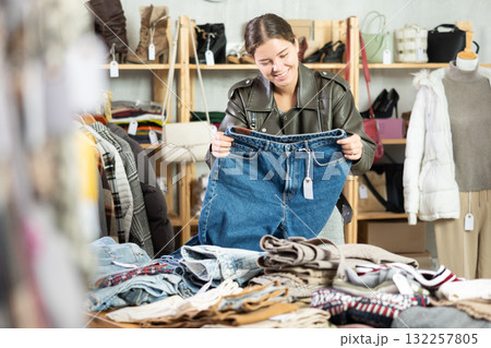 Positive young girl choosing jeans pantaloons in clothing store Positive young girl choosing jeans pantaloons in clothing store 132257805