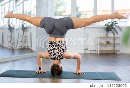 Fit woman performing advanced headstand yoga pose Fit woman performing advanced headstand yoga pose 132258006