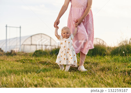 Helping baby to walk. Beautiful mother with her daughter on the farm 132259187