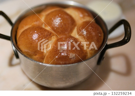 Bread rolls pot variety of fresh baked bread loaves wrapped in country style linens in a basket against rustic brick  132259234