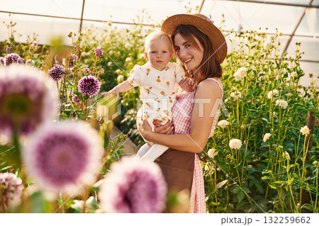 Bright sunlight. Baby is happy. Mother and daughter are in the greenhouse 132259662