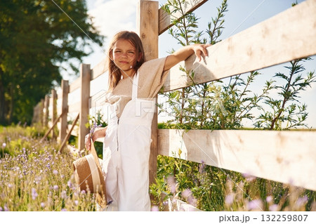 Leaning on the wooden fence. Cute little girl is on the farm 132259807