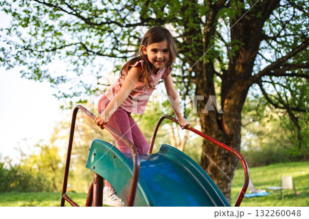Joyful moments on a playground slide during spring afternoon Joyful moments on a playground slide during spring afternoon 132260048