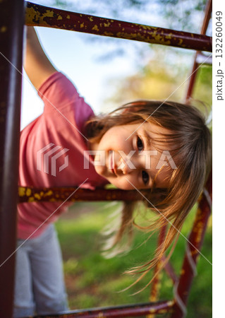 Joyful child playing on a playground in golden sunlight afternoon 132260049