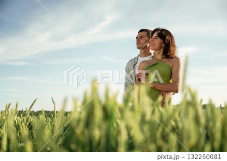 In green dress and white clothes. Lovely couple are on the agricultural field together In green dress and white clothes. Lovely couple are on the agricultural field together 132260081