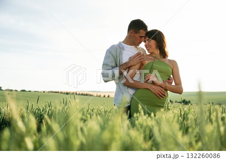 Standing and enjoying nature and each other. Lovely couple are on the agricultural field together Standing and enjoying nature and each other. Lovely couple are on the agricultural field together 132260086