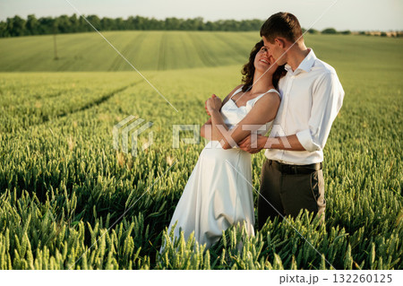 In formal wedding clothes. Lovely couple are on the agricultural field together In formal wedding clothes. Lovely couple are on the agricultural field together 132260125
