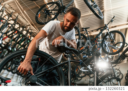 Final adjustments. Repair man in bicycle shop, working in store Final adjustments. Repair man in bicycle shop, working in store 132260321