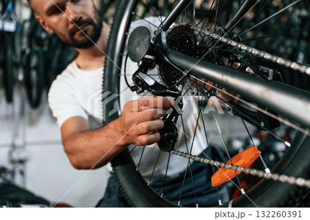 Derailleur adjustment. Repair man in bicycle shop, working in store 132260391
