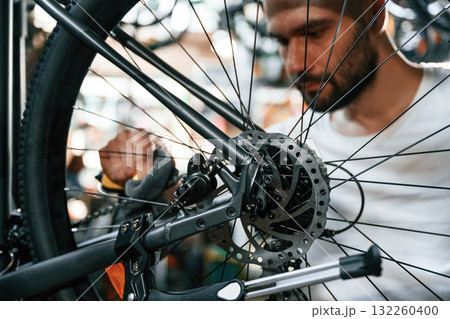 Cleaning the chain. Repair man in bicycle shop, working in store 132260400
