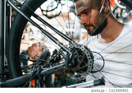 Cleaning the chain. Repair man in bicycle shop, working in store 132260401