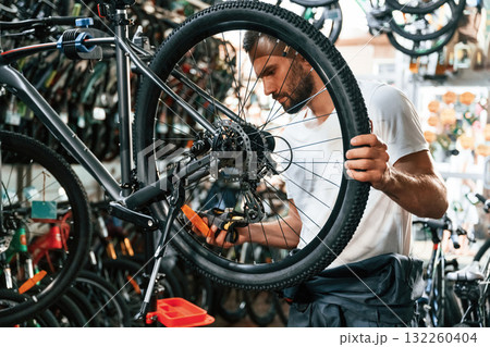 Focused at job. Repair man in bicycle shop, working in store Focused at job. Repair man in bicycle shop, working in store 132260404