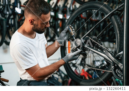 Spokes replacement. Repair man in bicycle shop, working in store 132260411