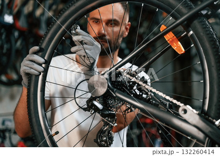 Spokes replacement. Repair man in bicycle shop, working in store Spokes replacement. Repair man in bicycle shop, working in store 132260414