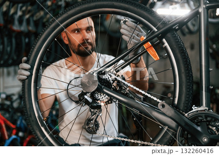Spokes replacement. Repair man in bicycle shop, working in store 132260416