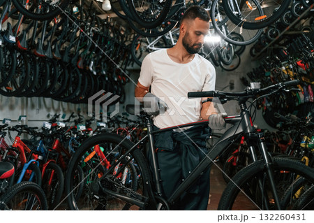 Indoors, many bikes. Repair man in bicycle shop, working in store Indoors, many bikes. Repair man in bicycle shop, working in store 132260431